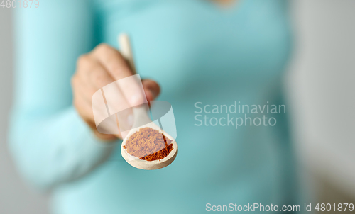 Image of close up of woman with turmeric on wooden spoon