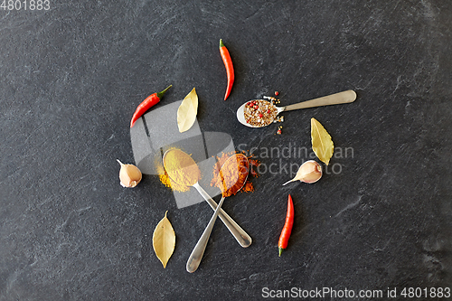 Image of spices, chili pepper, bay leaf and garlic on stone