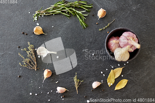 Image of garlic in bowl and rosemary on stone surface