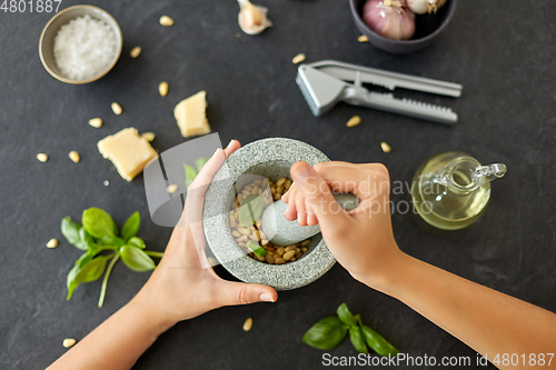 Image of hands grinding pine nuts in mortar and pestle