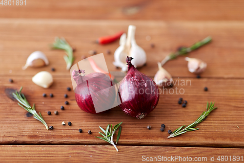 Image of onion, garlic, chili pepper and rosemary on table