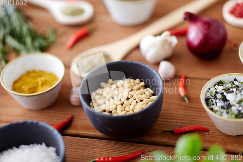 Image of pine nuts in bowl and spices on kitchen table