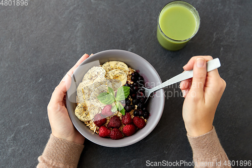 Image of hands of woman eating cereal breakfast with spoon