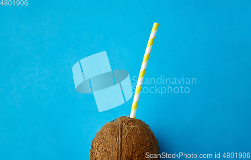 Image of coconut drink with paper straw on blue background