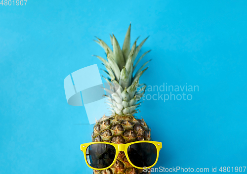 Image of pineapple in yellow sunglasses on blue background