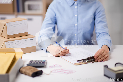 Image of woman with clipboard and parcels at post office