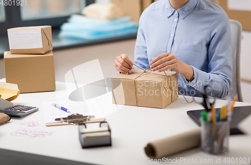 Image of woman packing parcel and tying rope at post office