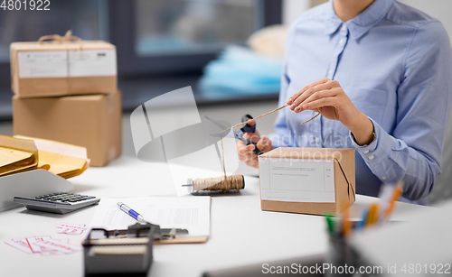 Image of woman with parcel cutting rope at post office