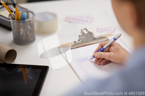 Image of woman with clipboard and parcels at post office