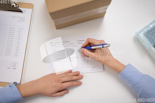 Image of close up of woman filling postal form at office