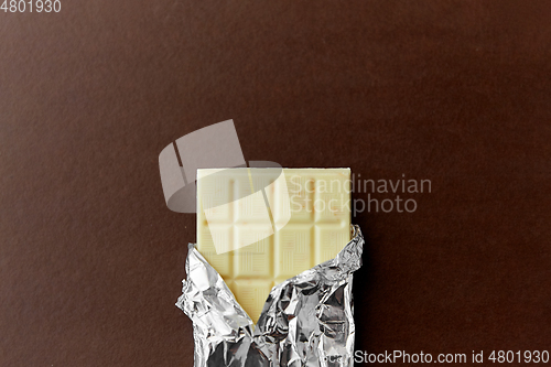 Image of white chocolate bar in foil wrapper on brown