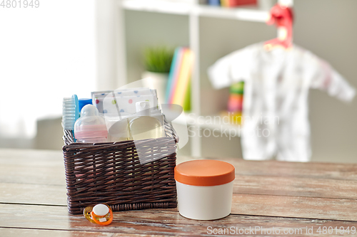 Image of baby things in basket on wooden table at home