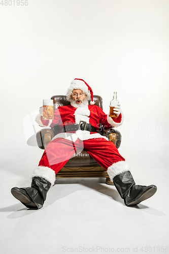 Image of Santa Claus drinking beer sitting on armchair, congratulating of New Year 2020