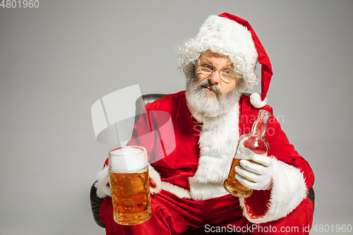 Image of Santa Claus drinking beer sitting on armchair, congratulating of New Year 2020