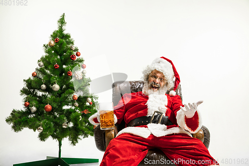 Image of Santa Claus drinking beer near Christmas tree, congratulating of
