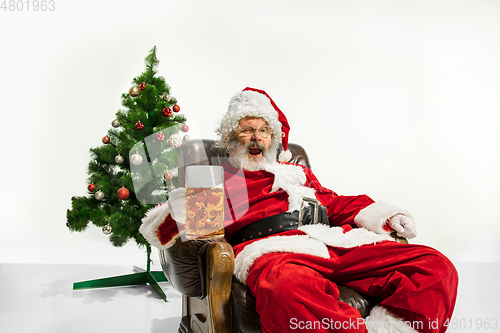 Image of Santa Claus drinking beer near Christmas tree, congratulating of