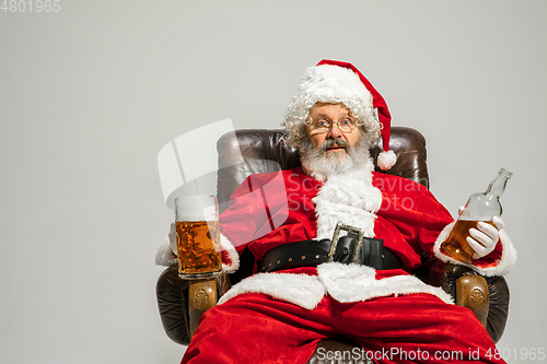 Image of Santa Claus drinking beer sitting on armchair, congratulating of New Year 2020