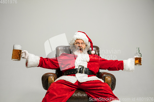 Image of Santa Claus drinking beer sitting on armchair, congratulating of New Year 2020