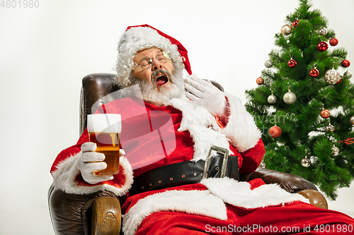 Image of Santa Claus drinking beer near Christmas tree, congratulating of