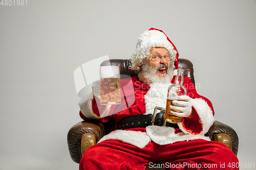 Image of Santa Claus drinking beer sitting on armchair, congratulating of New Year 2020