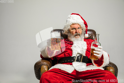 Image of Santa Claus drinking beer sitting on armchair, congratulating of New Year 2020