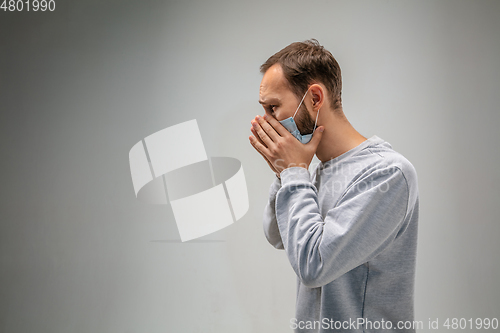 Image of Caucasian man wearing the respiratory protection mask against air pollution and dusk on grey studio background