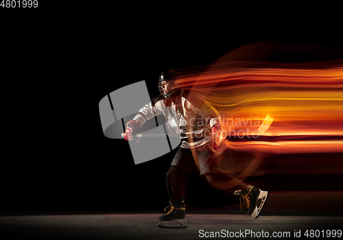 Image of Young female hockey player with the stick on black background in neon light