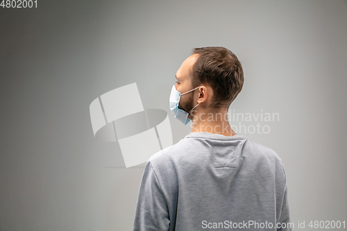 Image of Caucasian man wearing the respiratory protection mask against air pollution and dusk on grey studio background