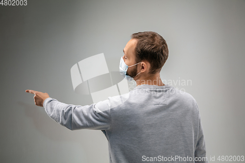 Image of Caucasian man wearing the respiratory protection mask against air pollution and dusk on grey studio background