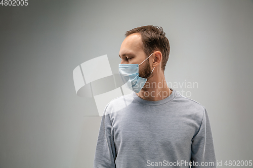 Image of Caucasian man wearing the respiratory protection mask against air pollution and dusk on grey studio background