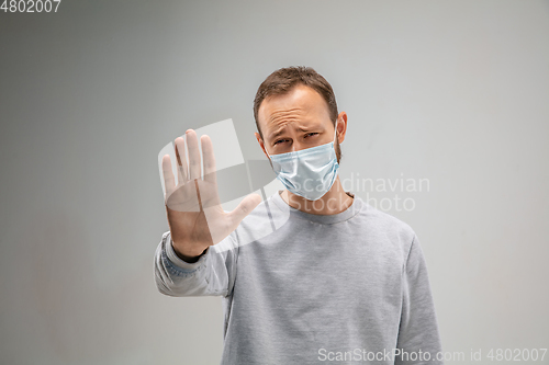 Image of Caucasian man wearing the respiratory protection mask against air pollution and dusk on grey studio background