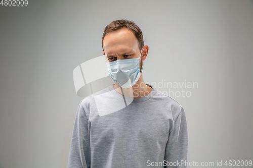 Image of Caucasian man wearing the respiratory protection mask against air pollution and dusk on grey studio background