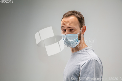 Image of Caucasian man wearing the respiratory protection mask against air pollution and dusk on grey studio background