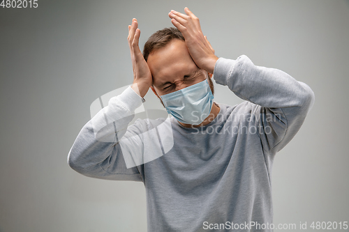 Image of Caucasian man wearing the respiratory protection mask against air pollution and dusk on grey studio background