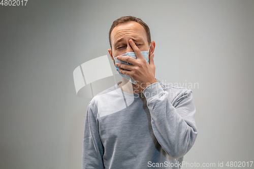 Image of Caucasian man wearing the respiratory protection mask against air pollution and dusk on grey studio background