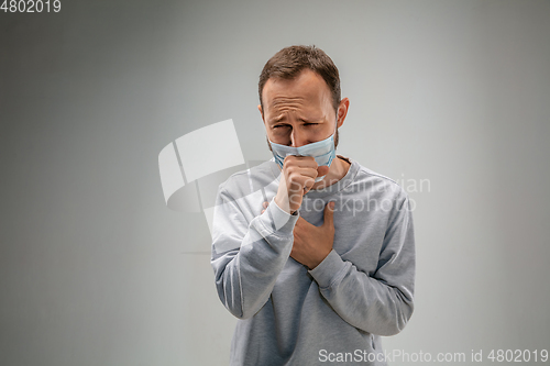 Image of Caucasian man wearing the respiratory protection mask against air pollution and dusk on grey studio background