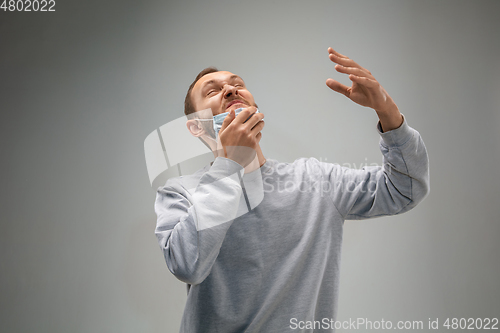 Image of Caucasian man wearing the respiratory protection mask against air pollution and dusk on grey studio background