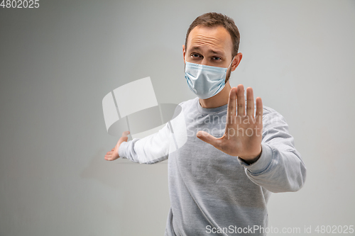 Image of Caucasian man wearing the respiratory protection mask against air pollution and dusk on grey studio background