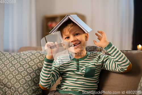 Image of happy little boy with book having fun at home