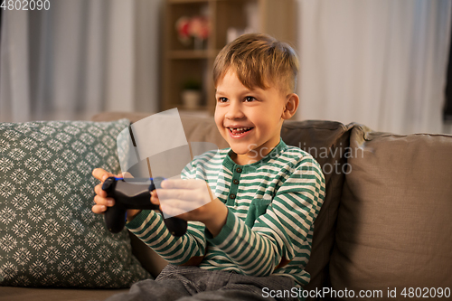 Image of little boy with gamepad playing video game at home