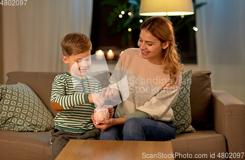 Image of mother and little son with piggy bank at home