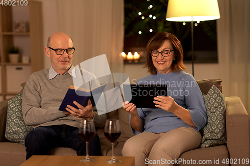Image of senior couple with book and tablet pc at home