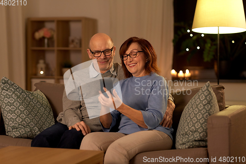 Image of happy senior couple with smartphone at home