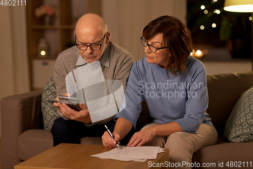 Image of senior couple with papers and calculator at home