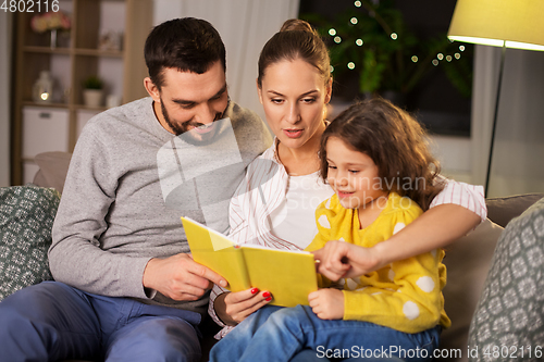 Image of happy family reading book at home at night