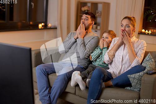 Image of scared family watching tv at home at night