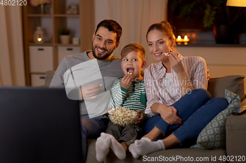 Image of happy family with popcorn watching tv at home