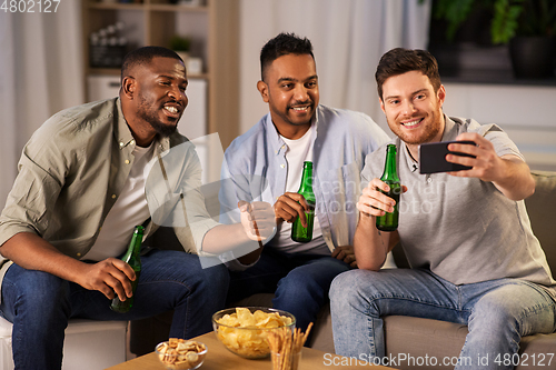 Image of male friends with smartphone taking selfie at home