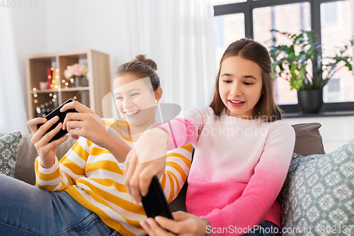 Image of girls and playing game on smartphones at home