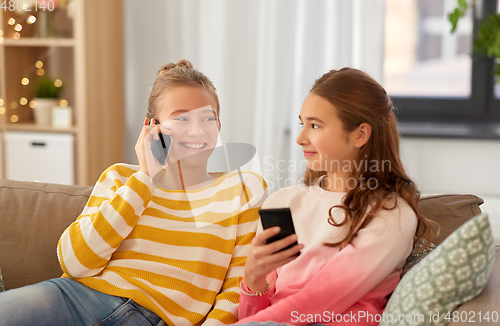 Image of happy teenage girls with smartphones at home